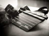 Movie clapper board and filmstrip selective focus and vintage black and white